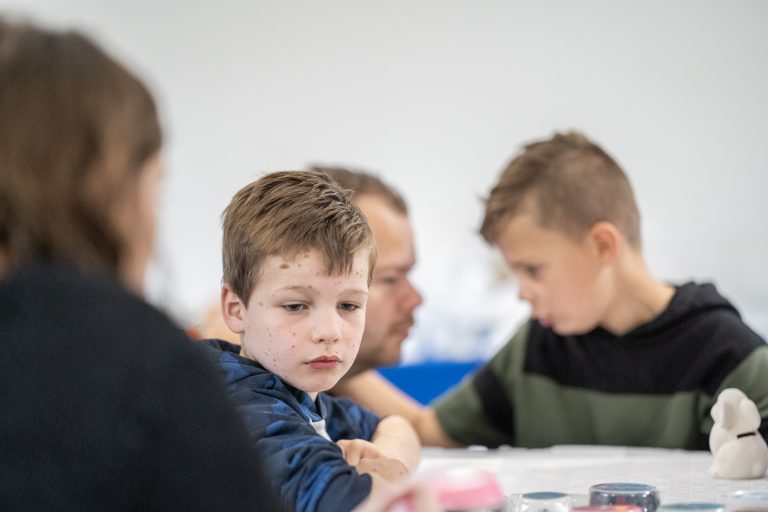jongen-kijkt-treurig_vader-en-zoon-op-achtergrond_onscherp_2023-11-04-10.49.19-2